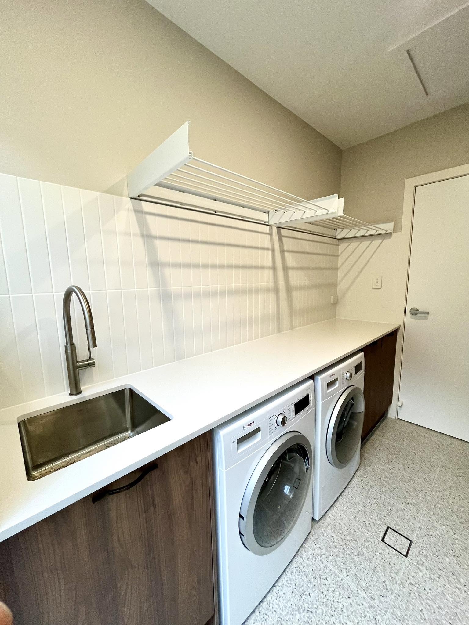Modern laundry with stone bench and dual Bosch washers