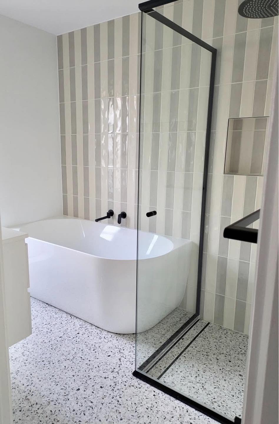Luxury bathroom renovation with freestanding bath and designer striped tiles by Spriggs and Co Adelaide