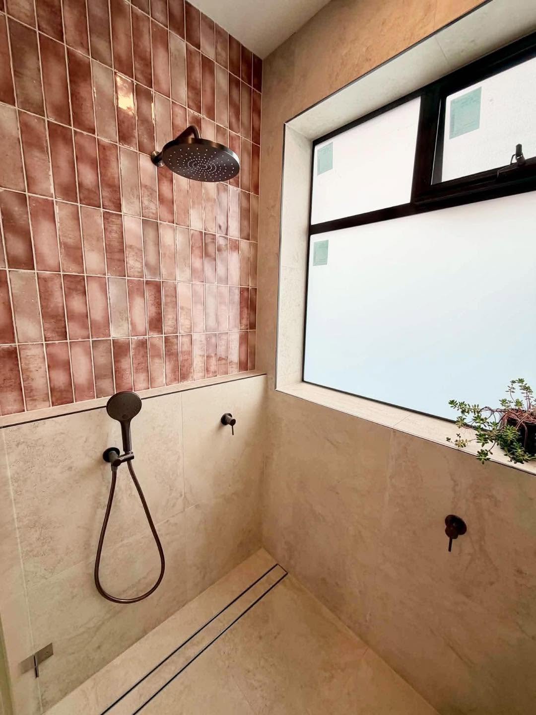 Walk-in shower with pink gloss feature tiles, rain shower head and black tapware
